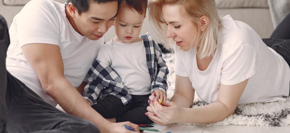 Loving family creating art together, fostering play and connection indoors.